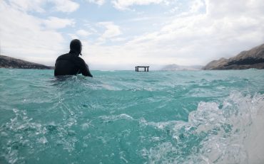 Surfing in wetsuit sitting on surfboard