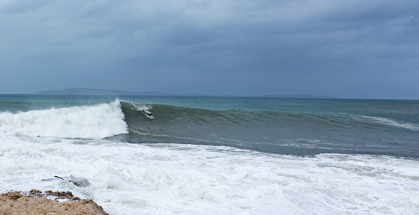 A left hand wave with a surfer catching it.