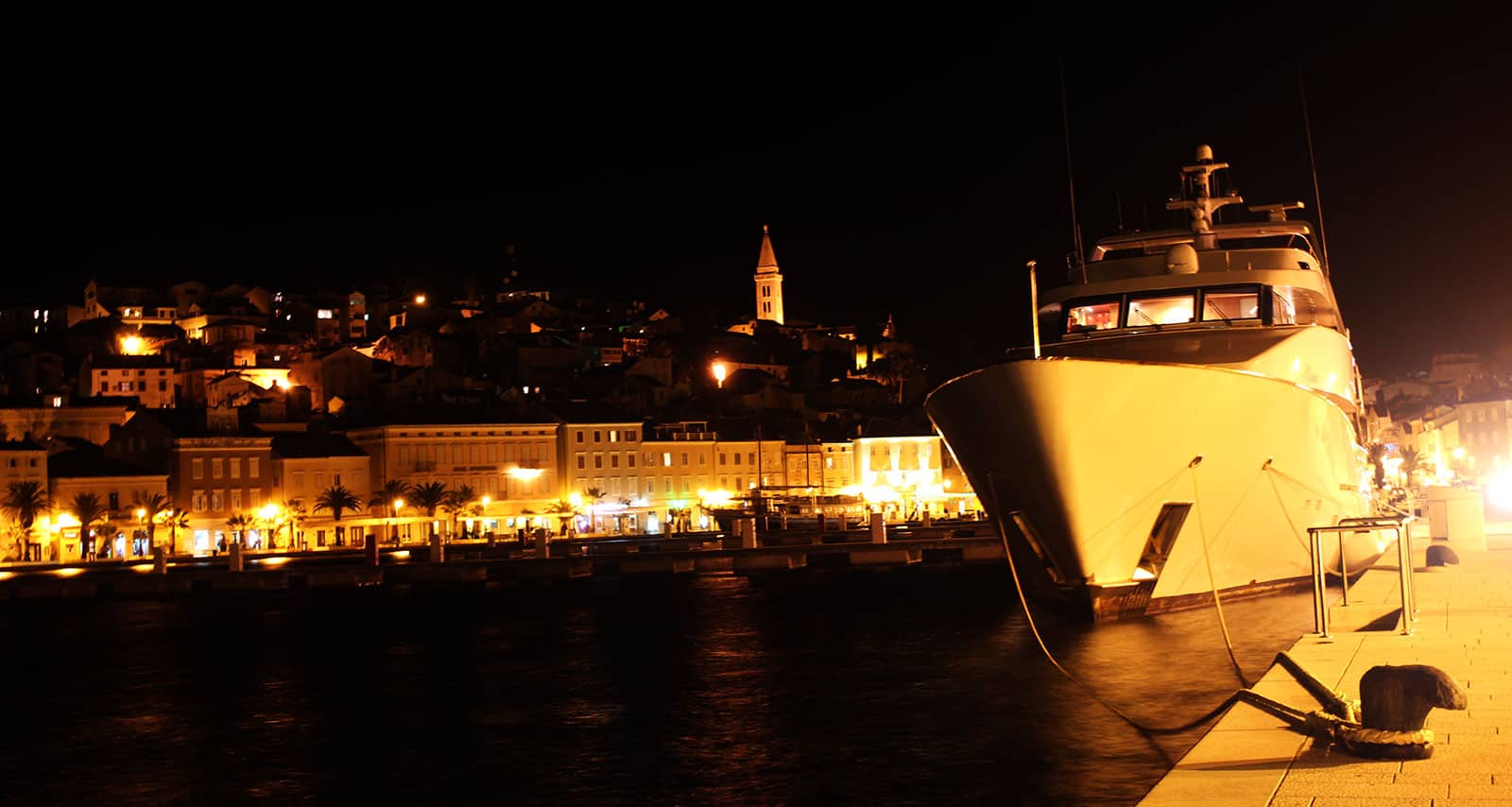 Seaside town at night with a big yacht.