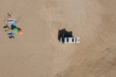 Van and people on the beach from above.